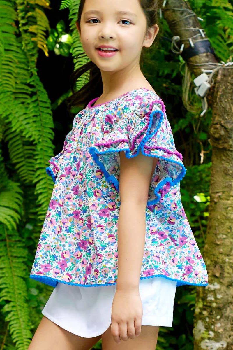 Une élégante blouse été à manches papillon et en coton fleuri liberty violette et bleue pour filles et fillettes de 2 à 16 ans de la marque créateur mode Française enfant LA FAUTE A VOLTAIRE.