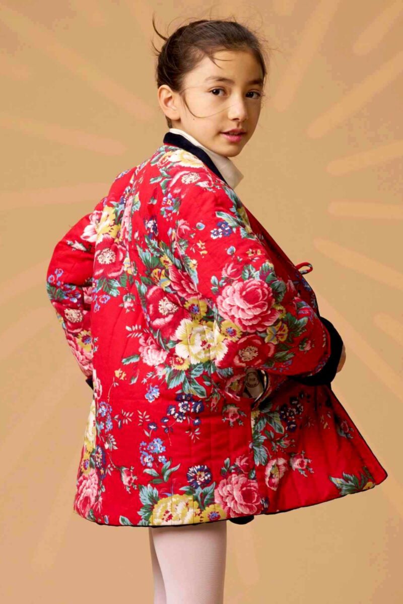 On Craque pour cette Magnifique Veste Matelassée d'inspiration Chinoise pour Fille en Velours Milleraies Bleu Marine à l'endroit et Coton Fleuri Asiatique Rouge sur l'envers. Le Col style Kimono se retourne si besoin pour faire apparaître la doublure contrastée. Vêtement évolutif avec les Manches qui se Retournent pour s'ajuster à Longueur des Bras de votre Fillette. Collection Vestes et Manteaux Tendances Automne Hiver de la Marque de Mode Enfantine La Faute à Voltaire.