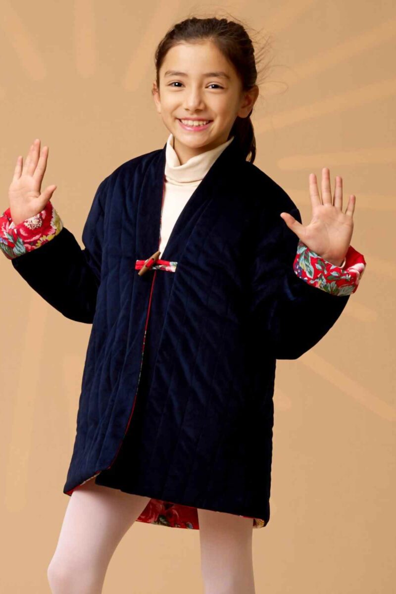 On Craque pour cette Magnifique Veste Matelassée d'inspiration Chinoise pour Fille en Velours Milleraies Bleu Marine à l'endroit et Coton Fleuri Asiatique Rouge sur l'envers. Le Col style Kimono se retourne si besoin pour faire apparaître la doublure contrastée. Vêtement évolutif avec les Manches qui se Retournent pour s'ajuster à Longueur des Bras de votre Fillette. Collection Vestes et Manteaux Tendances Automne Hiver de la Marque de Mode Enfantine La Faute à Voltaire.
